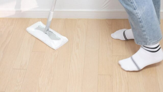 Woman cleaning floors with a mop, side view close-up.