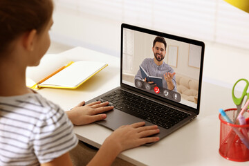 E-learning. Little girl using laptop during online lesson at table indoors