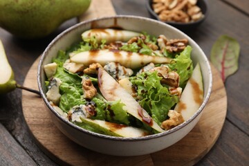 Delicious pear salad with sauce in bowl on wooden table, closeup