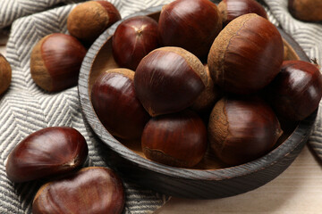 Sweet fresh edible chestnuts on light wooden table, closeup