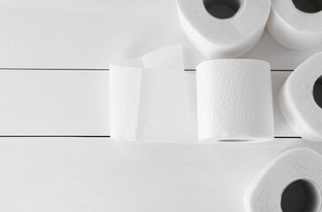Many soft toilet paper rolls on white wooden table, flat lay. Space for text