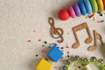 Baby song concept. Wooden notes, kids musical instruments and toys on beige carpet, flat lay. Space...