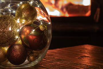 Colourful Christmas ornaments in front of cozy fire.