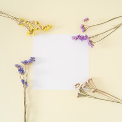 Creative layout made of colorful dry flowers with paper card note on pastel cream background. Floral greeting card. Minimal concept and simplicity. Nature decorative design. Flat lay.
