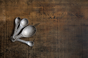 vintage metal measuring spoons with patina on a wood table with room for text