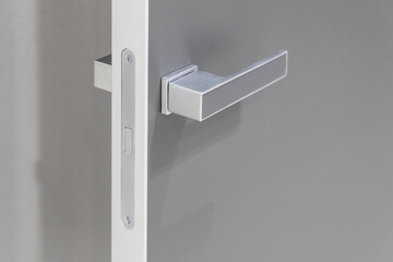 Gray door handle on a gray interior door. Magnetic lock on an open interior door, close-up. Silent...
