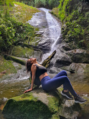 Woman sitting on a rock with a waterfall in the background