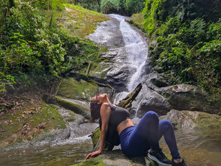 Woman sitting on a rock with a waterfall in the background