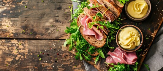 A platter showcasing a variety of meats and cheeses laid out on a rustic wooden table. The assortment includes ham, cheese, watercress, and salad greens, served on wholegrain brown bread. Side