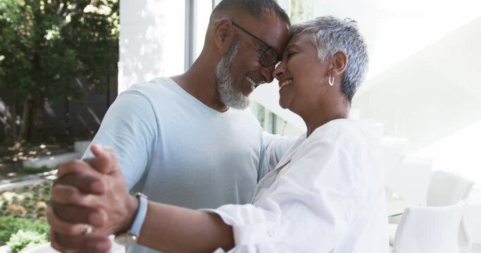 Biracial couple shares a tender moment, both with gray hair and glasses