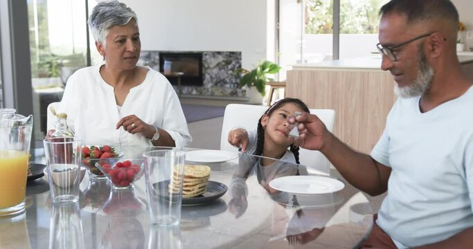 Biracial family enjoys breakfast, with a child reaching for food
