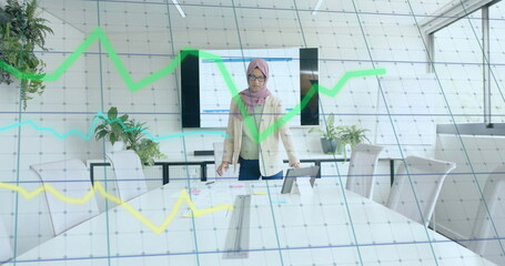 Image of financial data processing over biracial businesswoman in hijab working in office