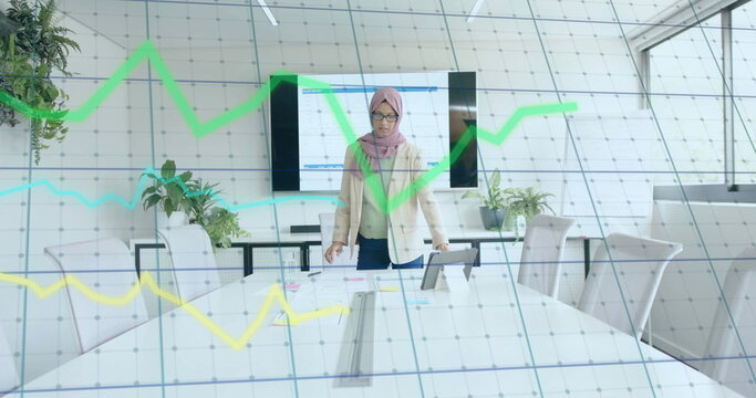 Image of financial data processing over biracial businesswoman in hijab working in office