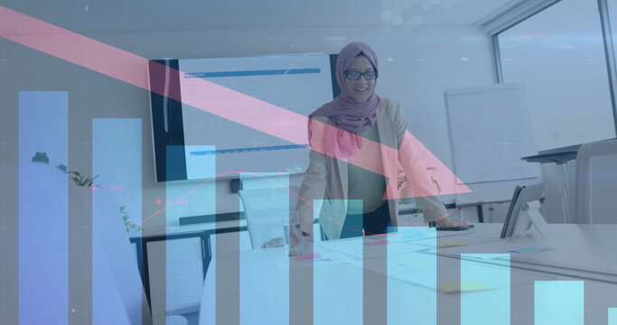 Image of financial data processing over biracial businesswoman in hijab working in office - Powered by Adobe