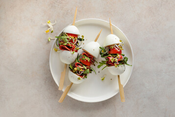 Boiled eggs and salami salad on skewers on a plate top view