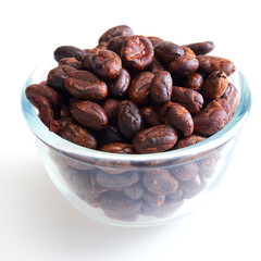 Roasted cocoa beans in a glass bowl on white