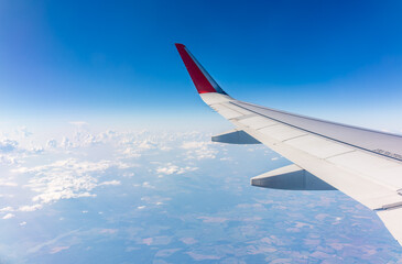 Obraz premium View from the airplane window at a beautiful cloudy sky and the airplane wing