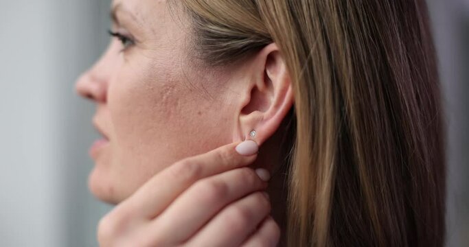 Beautiful woman puts long earring on ear