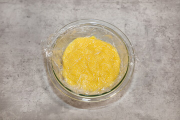 A bowl with custard cream covered with plastic wrap to keep it from crusting while it cools off.