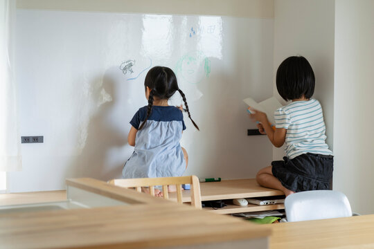 ホワイトボードにお絵描きをする姉妹