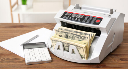 Modern cash counting machine with dollar banknotes, calculator and notebook on table in office - obrazy, fototapety, plakaty