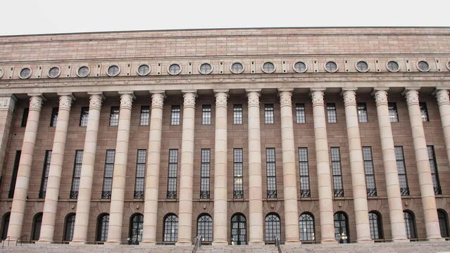 Wide shot of the Helsinki Parliament House fa&ccedil;ade on a cloudy day, no people in view, imposing architecture, camera tilt up
