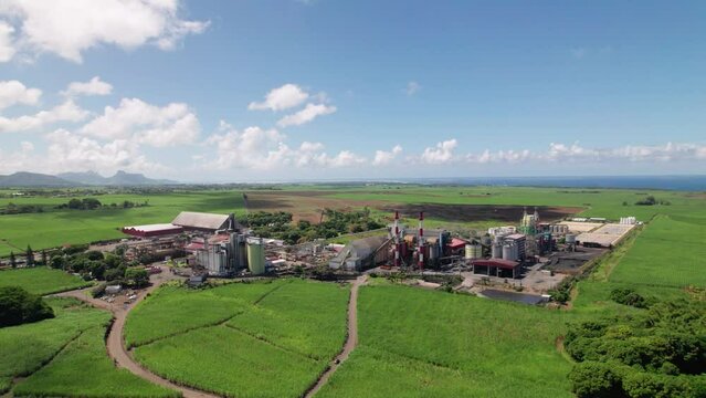 A sugar factory in mauritius amidst green fields under blue skies, industrial meets agriculture, aerial view