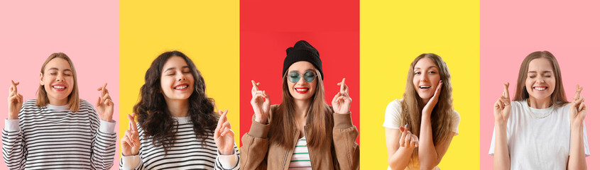Group of young women with crossed fingers on color background