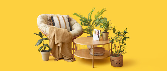Coffee table with photo of woman and houseplants near cozy armchair