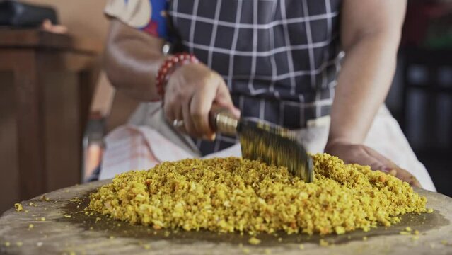 a Person is do chopping Balinese Herb Seasoning with Blakas, a Traditional Balinese Knife on the Wooden Board
