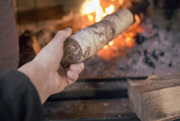 a hand puts a wood into a stove, indoor close up