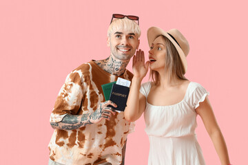 Young couple with passports on pink background