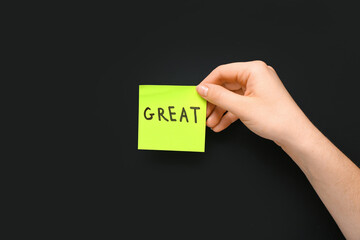 Female hand and paper with word GREAT on dark background. Customer experience concept