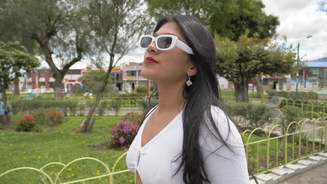 Cinematic close up clip of a young latin girl in sunglasses walking in confidence on a sunny day