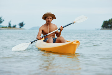 Happy Asian Man Enjoying Kayaking Adventure on a Tropical Beach