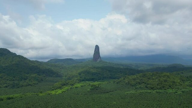 Flying towards Pico Cao Grande over the magnificent green forest on a sunny day with the peak exposed at São Tomé,Africa