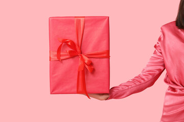 Beautiful young woman with gift box on pink background. Valentine's Day celebration