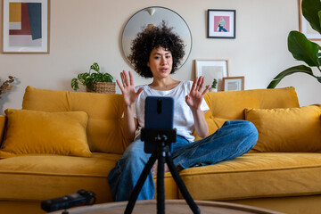 Young african american mixed race woman recording video talking to followers during live stream on...