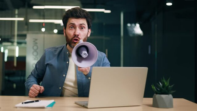 Bossy entrepreneur in casual outfit expressing negative emotions while yelling through bullhorn in workspace with pc. Cynical chef showing disrespect for employees at company office with glassy walls.