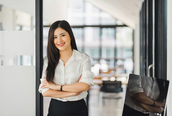 Confident Asian businesswoman smiling at camera at modern office.