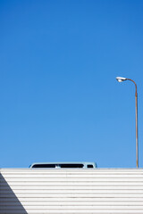 屋上駐車場の車と街灯と青空 - obrazy, fototapety, plakaty