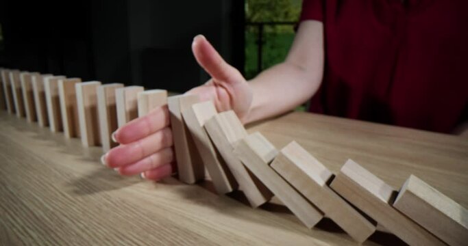 Hand will stop falling wooden domino blocks onto table