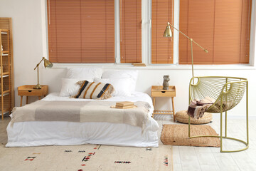 Interior of stylish bedroom with armchair and lamps