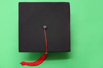 Graduation hat on green background