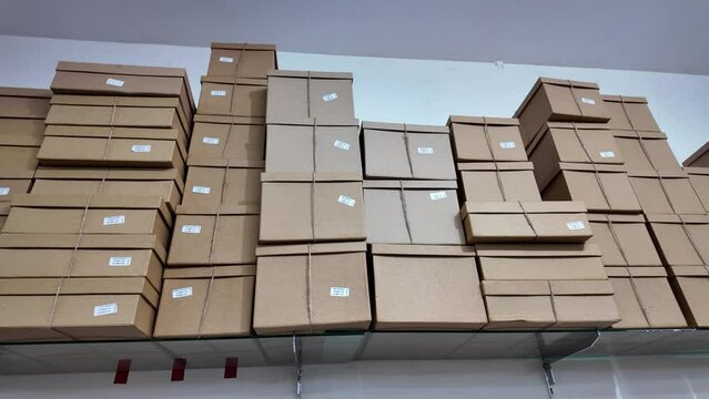 Stack of various cardboard boxes on a hanging rack in a packaging shop. Pile of carton giftbox with natural rope straps.