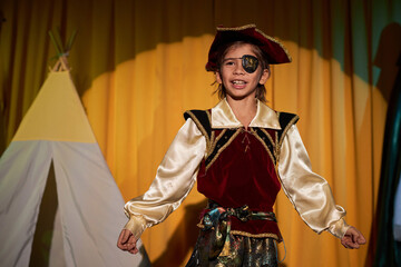 Waist up portrait of young boy wearing pirate costume performing on stage in school play