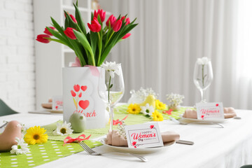 Beautiful table setting with greeting card and tulips for International Women's Day celebration
