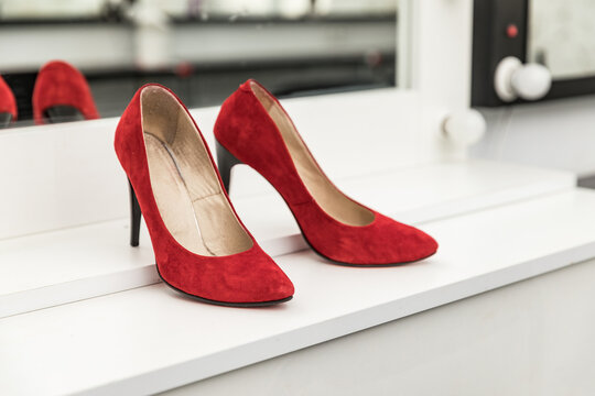 Red suede not new shoes on a white table for makeup