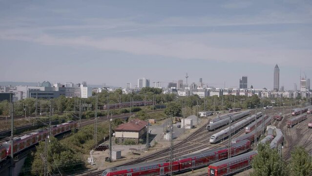 Panoramic view of Frankfurt's railway station with multiple trains and urban skyline in the background, daytime