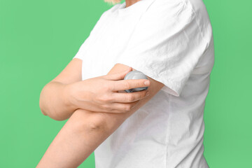 Woman with glucose sensor for measuring blood sugar level and applicator on green background, closeup. Diabetes concept